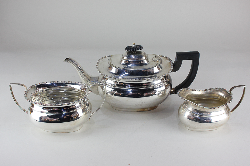 A silver plated three-piece tea set, oval shape with gadrooned border, including teapot, cream jug