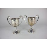 A pair of George V silver trophy cups with twin scroll handles on flared circular bases, each with