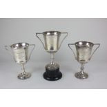 A set of three George V silver trophy cups with hexagonal knopped stems, one mounted on stand,