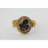 A Victorian gold mourning bangle with a central double faced locket with curled hair and seed