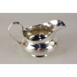 A William IV silver cream jug, circular form with reeded band and scroll handle, makers John,