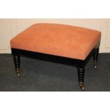 An upholstered rectangular stool with ebonised frame and turned legs on brass terminals and castors