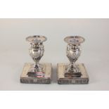 A pair of Victorian silver dwarf candlesticks, urn shape cast with rams' heads and swags, on