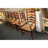 A matched set of five oak ladderback rush seated dining chairs including one carver, with shaped