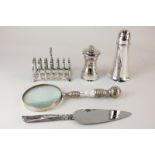 A silver plated pepper mill, a magnifying glass, a toast rack, a Walker & Hall sugar shaker, and a