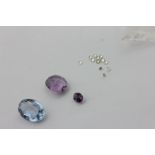 A collection of small faceted unmounted round diamonds, an amethyst, and a pale blue stone