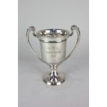 A George V silver two handled trophy cup with leaf capped scroll handles, knopped circular base,