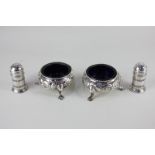 A matched pair of Victorian silver cauldron salts with embossed floral scrolling design on hoof