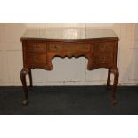 A walnut serpentine dressing table with cross-banded top above an arrangement of five drawers,