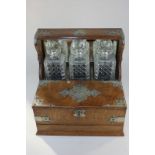 A Victorian metal mounted oak tantalus with three cut glass spirit decanters, over a cigar box, with