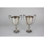 A pair of George V silver twin handled trophy cups with knopped stems and presentation inscriptions,