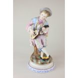 A Continental bisque porcelain figure of a boy playing a guitar, seated on a tree stump, with gilt