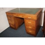 A mid-20th century oak pedestal desk, rectangular top with green inset top, centre drawer flanked by