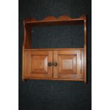 A small pine hanging kitchen wall cabinet with two shelves and cupboards, and shaped fret cut top,