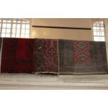 A Persian style wool rug with stylised floral centre, pink and blue flowers on red field within