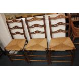 A set of three rush seated dining chairs, each with pierced horizontal bar back, on turned legs (a/