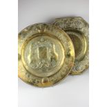 Two brass wall plaques with embossed decoration, one decorated with a coat of arms, stamped J Co