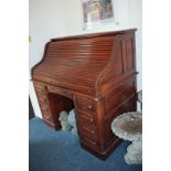 An early 20th century oak roll-top desk with piano shaped tambour front enclosing fitted interior of