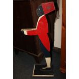 A painted wood figure of a waiter wearing a red fez with Royal Army Ordnance Corps cap badge, and