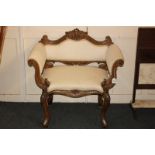 An upholstered dressing table chair with upholstered back and arms, carved scroll frame on
