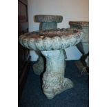 A stone composition garden bird bath, circular top on associated cast dolphin base, another bird