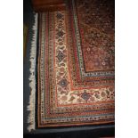 A large Persian style carpet with all-over floral decoration and central motif within multiguard