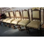 A set of five Flemish style carved oak dining chairs with brass studded panelled backs, scroll