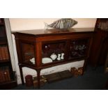 A narrow mahogany break-front display cabinet with two glazed panel doors enclosing a glass shelf,