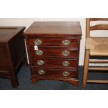 A small mahogany chest of four drawers with decorative brass embossed back plates and drop