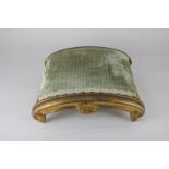 A 19th century carved giltwood footstool with green velvet upholstery, on scroll form, 32.5cm