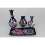 Three Moorcroft pottery vases in anemone, fruit and berry, and clematis patterns, together with a