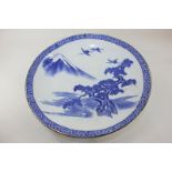 A Japanese porcelain blue and white charger depicting two storks flying over a tree with Mount