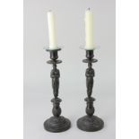 A pair of bronze figural candlesticks modelled as two caryatids, on circular bases, 27.5cm high