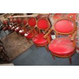 A set of eight red leather upholstered dining chairs, each with oval studded back and padded seat,