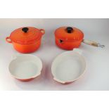 A Le Creuset orange enamel casserole dish and cover, saucepan with lid, oval dish, and circular