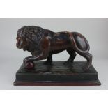 A pottery model of a lion with paw resting on a ball, painted to imitate bronze (a/f), 36.5cm