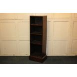 A modern narrow mahogany bookcase with rectangular top above three fixed shelves, on plinth base,