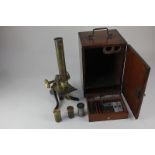 A brass student's microscope with wooden carry case, three lenses, and a collection of glass