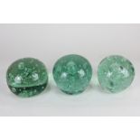 Three green glass dump paperweights / doorstops with bubbles