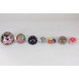 A collection of seven glass paperweights with floral decoration, to include a Selkirk glass flower