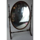 A mahogany oval framed dressing table mirror on turned supports and splayed legs, 68cm high