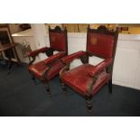 A pair of early 20th century carved oak baronial style armchairs, with red leather panelled backs,