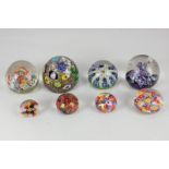 A collection of eight glass paperweights, comprising a Caithness Myriad paperweight with swirled
