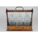 A metal mounted oak three glass decanter tantalus, with lock and key, one decanter with chip to rim,