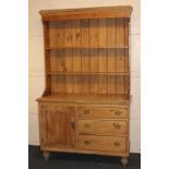 A pine dresser, with closed two shelf plate rack, on base with cupboard and three drawers, on turned