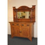 An Arts & Crafts Liberty style oak sideboard, raised back with shelf and mirror carved with stylised