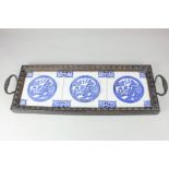 A Victorian carved oak tray, with three willow pattern porcelain tiles, the two handles