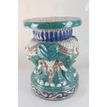 A glazed pottery stool decorated with elephants, in red, blue and green, circular top 28cm
