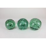 Three green glass dump paperweights/doorstops with bubble inclusion, largest 11.5cm high