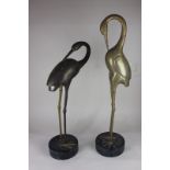 A pair of brass models of storks on black marble bases, 63cm high